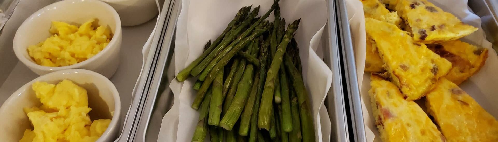 A platter featuring scrambled eggs, asparagus, and frittata slices.