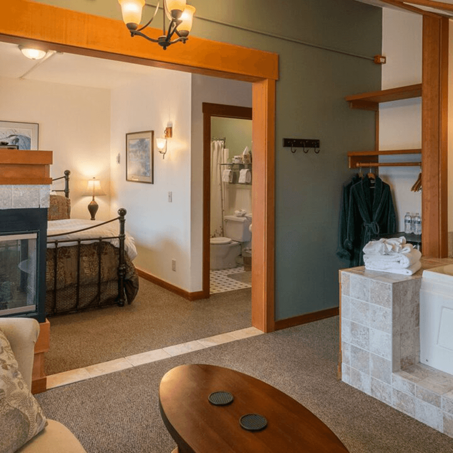 Cozy hotel suite featuring a bedroom with a fireplace, bathroom, and seating area.
