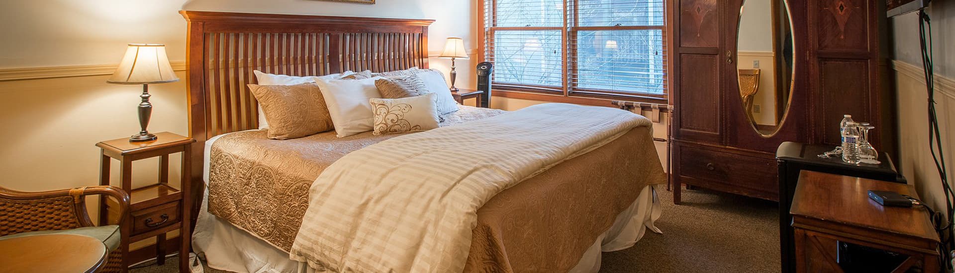 Cozy bedroom featuring a large bed, wooden furniture, and window light.