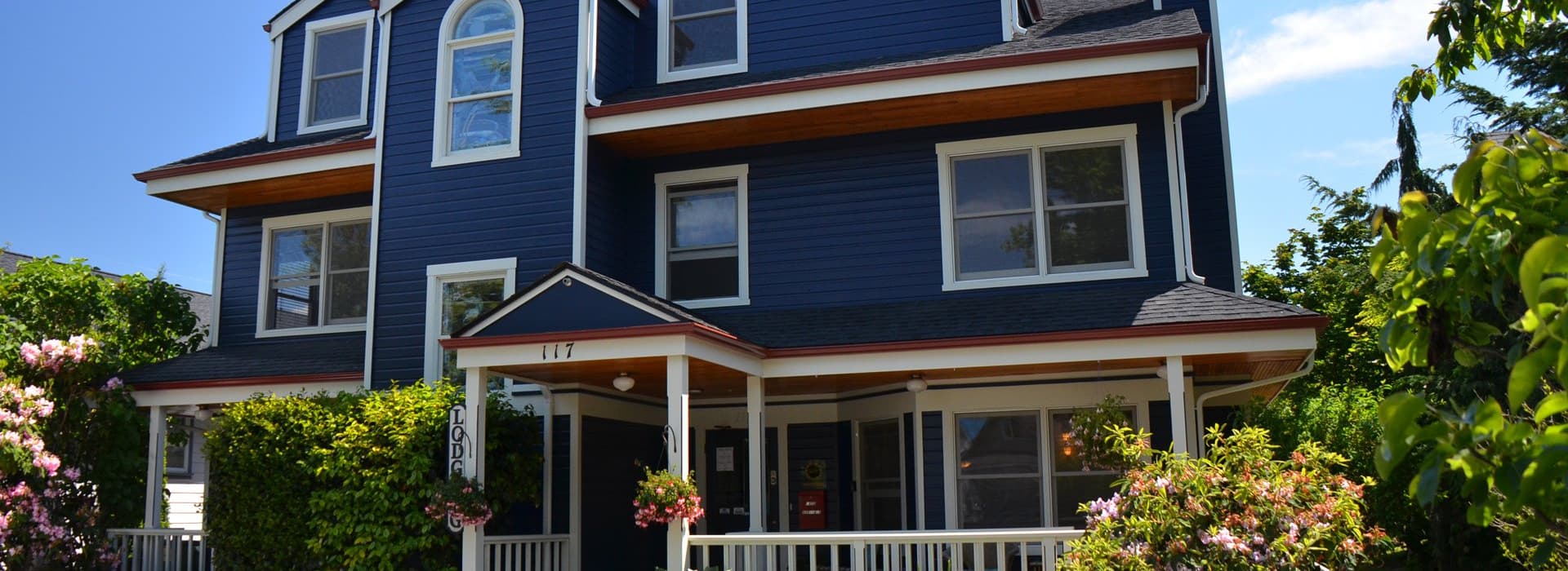 A blue house with a porch and colorful flowers in front.
