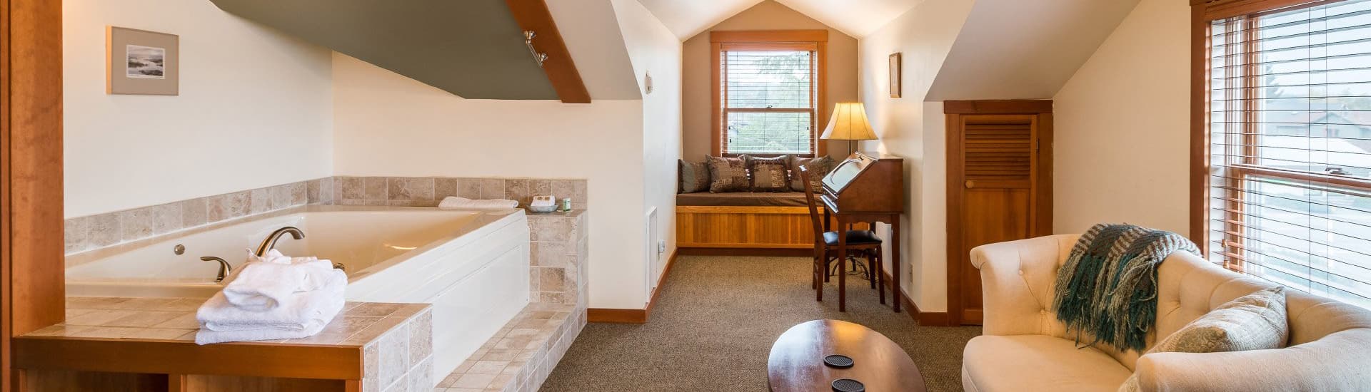 A cozy bathroom suite featuring a jacuzzi, comfortable seating area, and warm natural light.