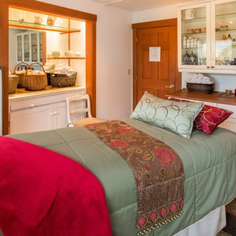 A cozy bedroom featuring a neatly made bed with decorative pillows, warm colors, and organized shelves.