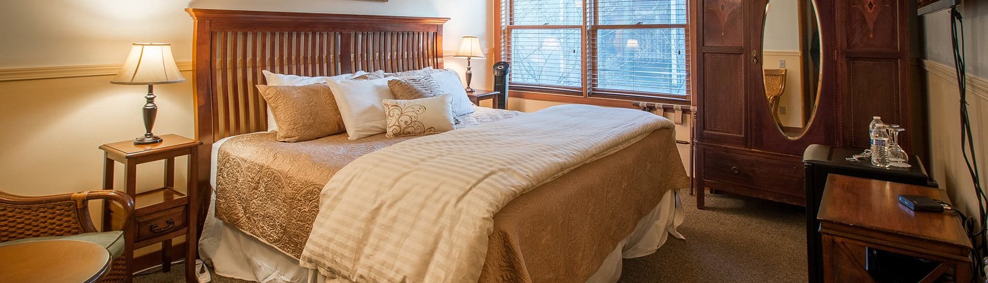 Cozy bedroom featuring a wooden bed, decorative pillows, and natural light from large windows.